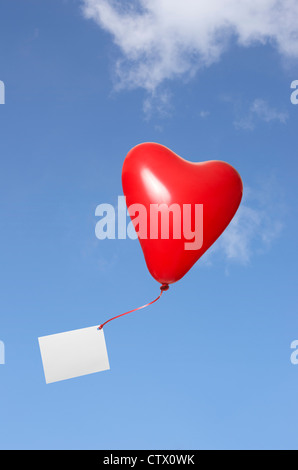 Cuore rosso palloncino con biglietto di auguri nel cielo Foto Stock