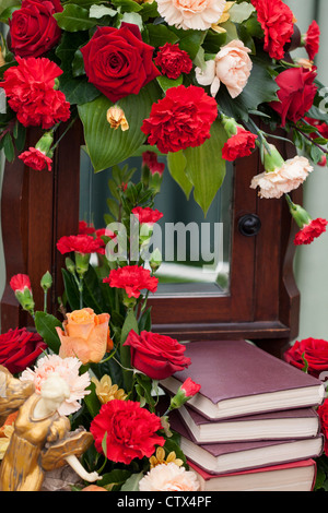 Un display floreale con uno specchio e libri Foto Stock