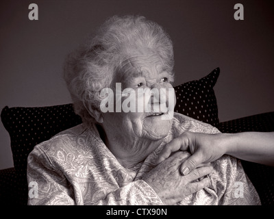 Felice rilassata senior vecchiaia pensionato donna anziana detiene consolante mano del caregiver nella sua casa soggiorno ( B&W) Foto Stock