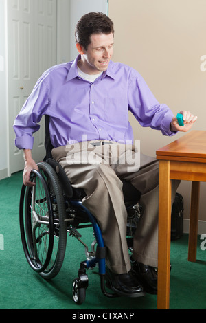 Uomo in carrozzella con lesioni del midollo spinale di prelevare la pillola caso; quadriplegic problema con destrezza manuale Foto Stock