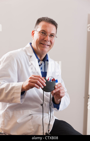 Audiologist tenendo un dispositivo auditivo programmer Foto Stock