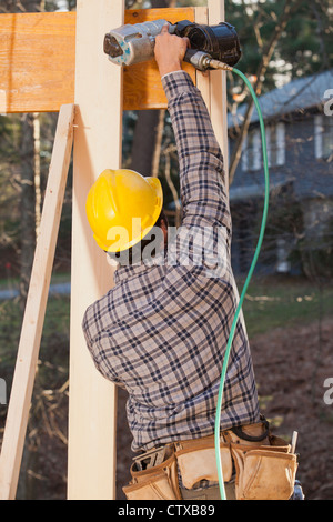 Carpenter utilizzando una pistola sparachiodi sulla trave Foto Stock