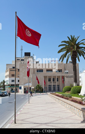 Una banca centrale della Tunisia edificio nella città di Sousse, Tunisia. Bandiere nazionali su strada Foto Stock