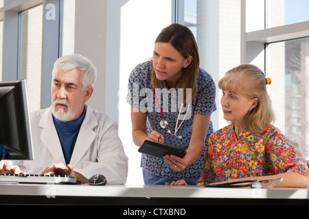 Due Infermieri e un medico che lavorano su computer e tablet Foto Stock