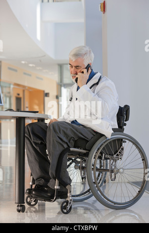 Medico con la distrofia muscolare in carrozzella parlando sullo smartphone Foto Stock