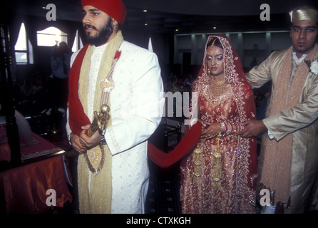 Sikh nuppiali con marito e moglie che camminano intorno al palki. Tiene la sciarpa tradizionale ed è assistita dal fratello, Londra. Foto Stock