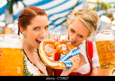 Giovani donne in tradizionali abiti bavarese - dirndl o tracht - su un festival o Oktoberfest in una tenda di birra Foto Stock