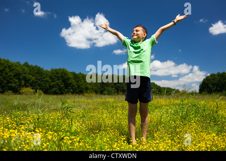 Felice ragazzo in un campo nei pressi della foresta Foto Stock