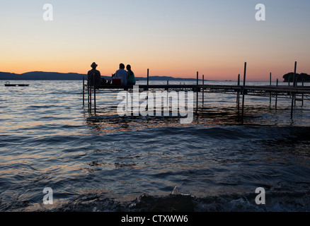 Un gruppo di persone guardare il tramonto da una dock sul Lago Champlain a Charlotte nel Vermont. Foto Stock