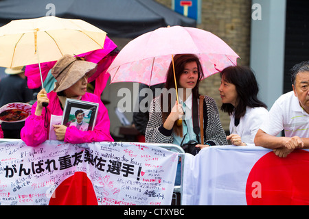 Atletica giapponese sostenitori di attendere nella pioggia per le donne di maratona, Olympic Games, Londra, 2012. Foto Stock