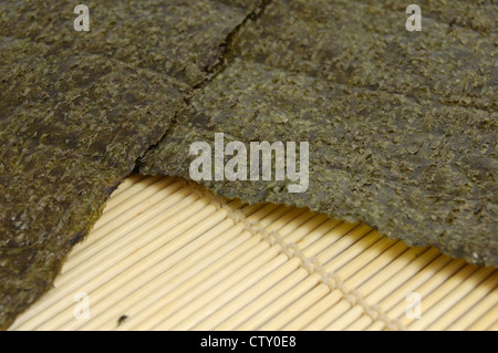 Verde essiccata sushi nori foglio su un tappetino di bambù Foto Stock