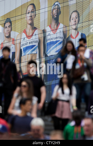 Con il gigante presenza del Team GB ruolo modello di atleta eroi dietro di loro, spettatore folle scendere una scalinata al Westfield Shopping Complex, Stratford che conduce al Parco Olimpico durante le Olimpiadi di Londra 2012, la trentesima Olimpiade. L'annuncio è per calzature sportive marca Adidas e loro "prendere la fase " campagna, compresi subacqueo Tom Daley, ginnasta Louis Smith, triple ponticello Phillips Idowu e il Darling britannica di atletica leggera, heptathlete medaglia d'oro Jessica Ennis. Foto Stock