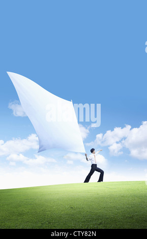 Un imprenditore sventolare la bandiera nel campo verde Foto Stock