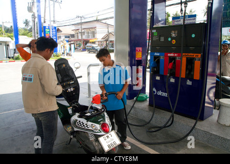 Gas station attendant riempiendo uno scooter a motore sull isola di Ko Samui, Thailandia. Foto Stock