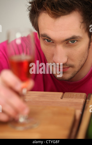 Determinato un uomo guarda un bicchiere di vino Foto Stock