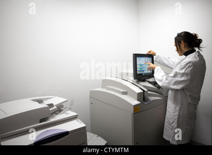 Giovani donne medico opera l'apparecchiatura di stampa nel reparto di radiologia in ospedale Foto Stock