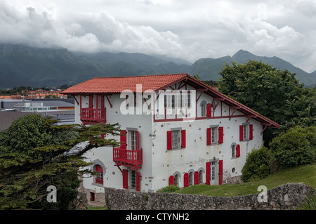 Casa tipica delle Asturie con facciata bianca e rossa in telai di porte e finestre, i picchi d'Europa sullo sfondo, in Llanes, Asturias, Spagna. Foto Stock