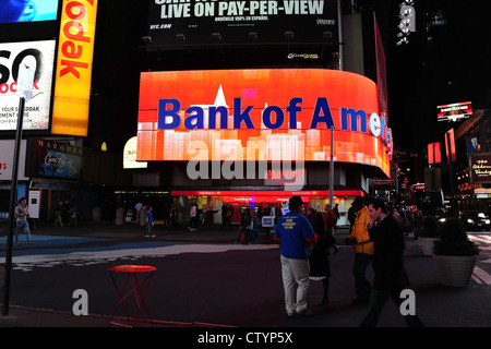 Notte Vista al neon, Bank of America, maglietta blu ticket agente a piedi Times Square, settima Avenue a West 46th Street, New York Foto Stock