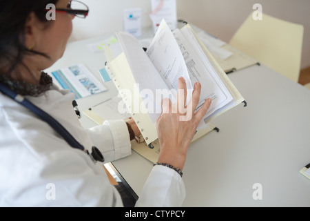 Medico donna di smistamento di documenti cartacei Foto Stock