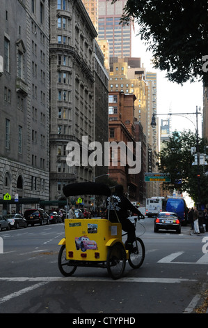 Pomeriggio giallo verticale pedicab in movimento nella West 59th Street da Central Park West Drive, verso la settima Avenue, New York Foto Stock