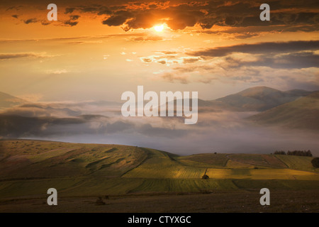 Tramonto nel cielo drammatico su campi Foto Stock