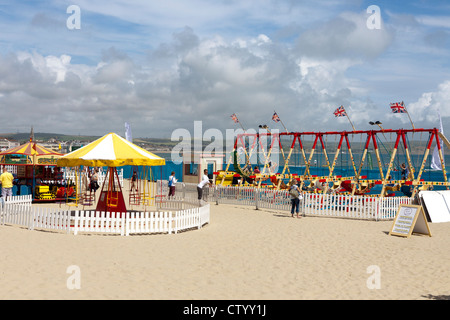 I bambini di giostre sulla spiaggia di Weymouth nel Dorset Foto Stock