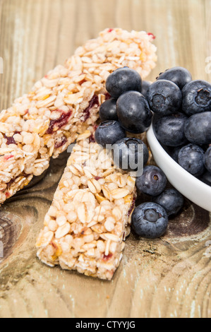 Muesli Bar con mirtilli in una ciotola su una tavola di legno Foto Stock