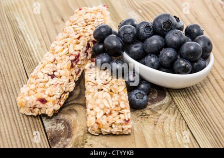 Muesli Bar con mirtilli in una ciotola su una tavola di legno Foto Stock