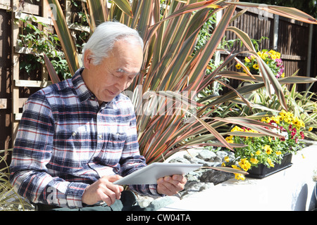 Uomo anziano utilizzando computer tablet all'aperto Foto Stock