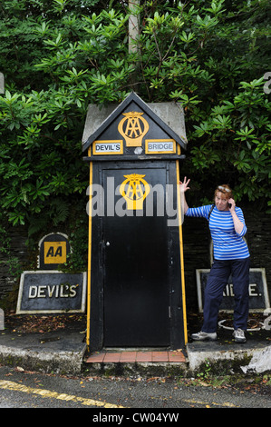 Donna che utilizza il telefono cellulare accanto a AA casella telefono Ponte del Diavolo Wales UK Foto Stock