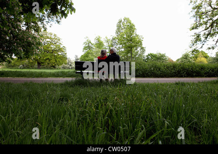 Coppia di anziani seduti su una panchina nel parco Foto Stock