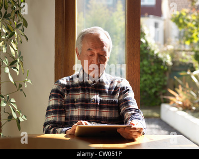 Uomo anziano utilizzando computer tablet a tavola Foto Stock