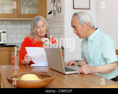 Coppia di anziani di pagare le bollette online Foto Stock