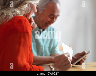 Coppia di anziani la lettura della posta in cucina Foto Stock