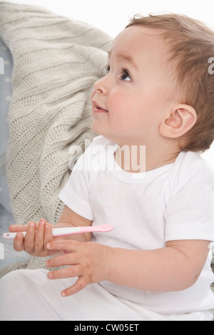 Sorridente baby giocando con cucchiaio in plastica Foto Stock