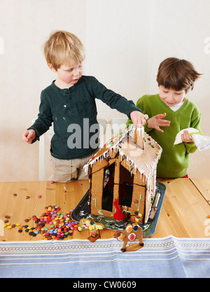 Ragazzi decorare gingerbread house Foto Stock