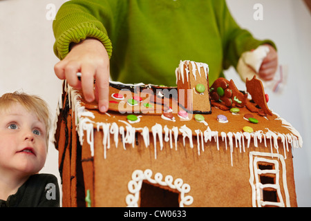 Ragazzi decorare gingerbread house Foto Stock