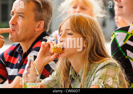 Piuttosto caucasica ragazza adolescente con lunghi capelli biondi mangia un panino - Ritratto, Heilbronn Germania Foto Stock