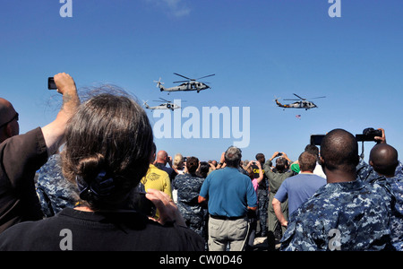 I marinai assegnati alla portaerei di classe Nimitz USS Abraham Lincoln (CVN 72) si uniscono ad amici e familiari sul ponte di volo della nave per guardare gli elicotteri MH-60S Seahawk assegnati ai Golden Falcons dello Squadrone di combattimento marittimo dell'elicottero (HSC) volare in formazione durante una dimostrazione di potenza aerea. Lincoln sta ritornando negli Stati Uniti dopo il completamento di un cambio di otto mesi di distribuzione di homeport durante il quale operò nelle aree di responsabilità della flotta degli Stati Uniti 5, 6 e 7. Foto Stock