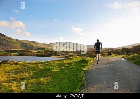 Uomo che corre sulla strada rurale Foto Stock