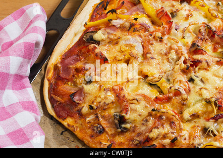 Freschi di forno Pizza col prosciutto, peperoni e verdure su una teglia da forno, close-up come dettaglio per il cibo italiano Foto Stock