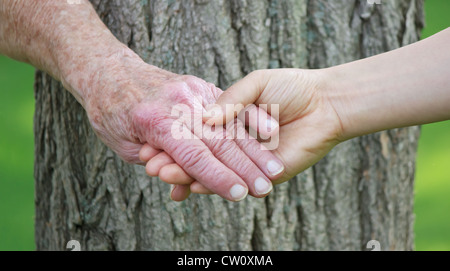 Signora Senior e Giovani custode tenendo le mani Foto Stock