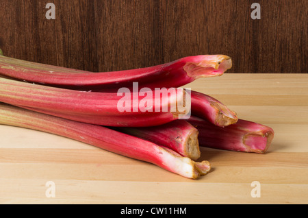 Gli stocchi di rabarbaro raggruppati su una tavola di legno Foto Stock