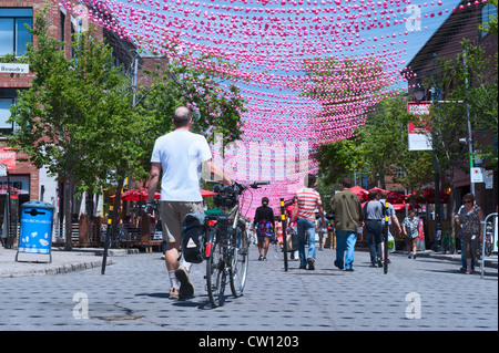 Uomo che cammina la sua bici su una parte Ste Catherine Street che è chiuso alle auto durante i mesi estivi. Villaggio Gay, Montreal. Foto Stock