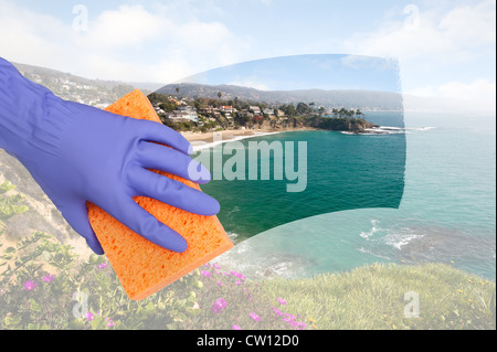 Una cameriera pulizia di Windows su una scogliera a casa che si affaccia su una insenatura lungo l'oceano. Foto Stock