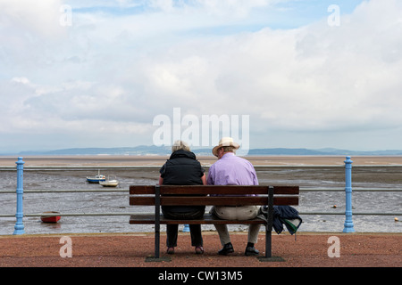 Maschio Femmina giovane seduta su una panchina che guarda al mare in Morecambe, Lancashire Foto Stock