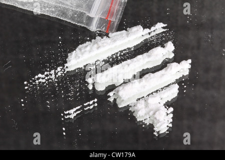 La cocaina in polvere in linee e il pacchetto sullo specchio Foto Stock