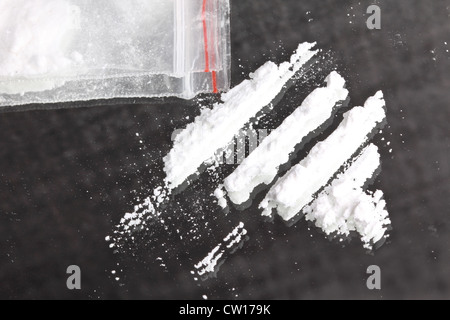 La cocaina in polvere in linee e il pacchetto sullo specchio, primo piano Foto Stock