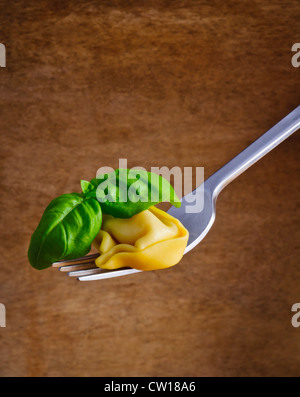 Tortellini e basilico su una forcella contro un annata sullo sfondo di legno Foto Stock