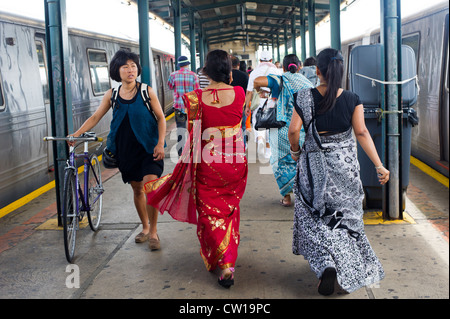 Donne abbigliate in sari passa una donna asiatica a piedi la sua bicicletta alla metropolitana in Richmond Hill nel Queens a New York Foto Stock